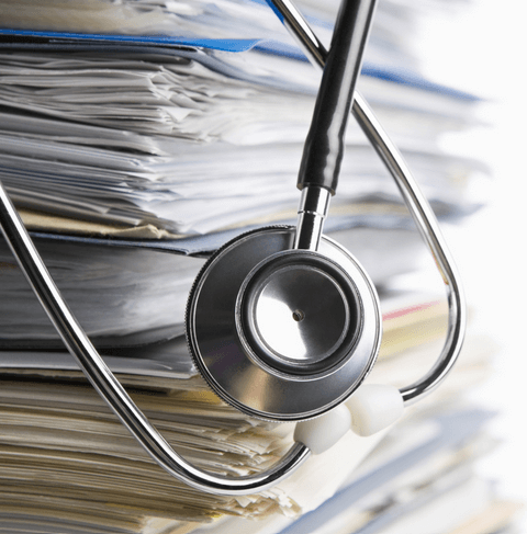 A stethoscope atop a stack of medical credentialing services documents