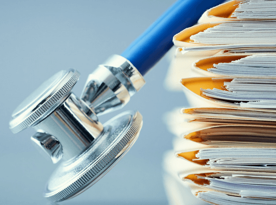 A stethoscope atop medical credentialing files