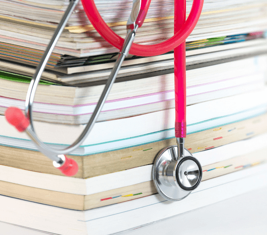 A large stack of hospital records and a stethoscope